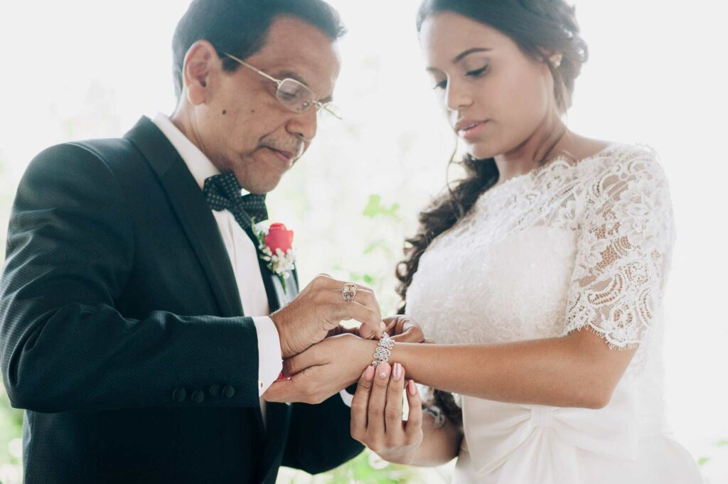 el padre le coloca una pulsera a la novia