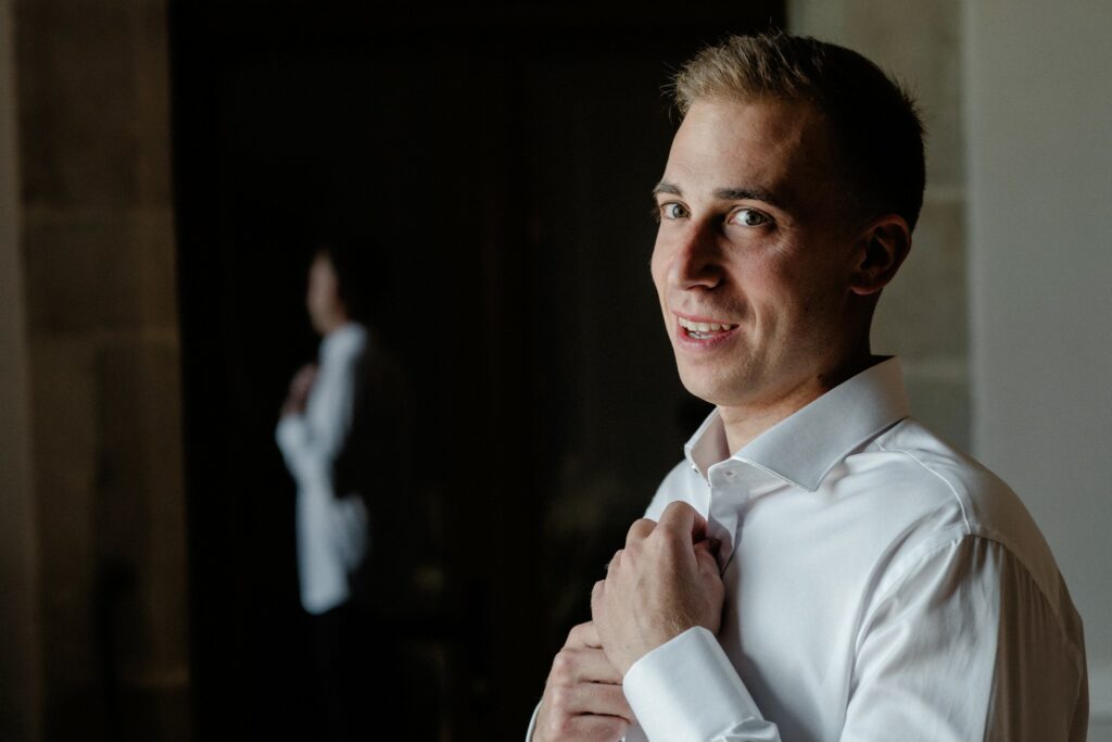 Novio sonriendo y abrochándose la camisa