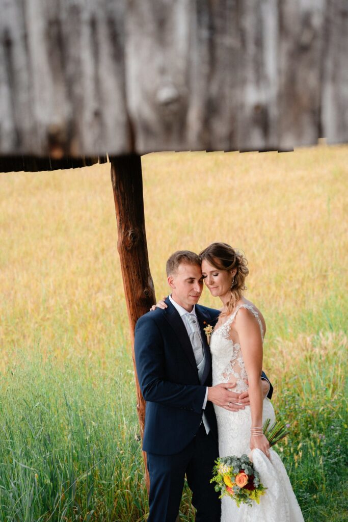 los novios cogidos de la cintura apoyados en un poste de madera